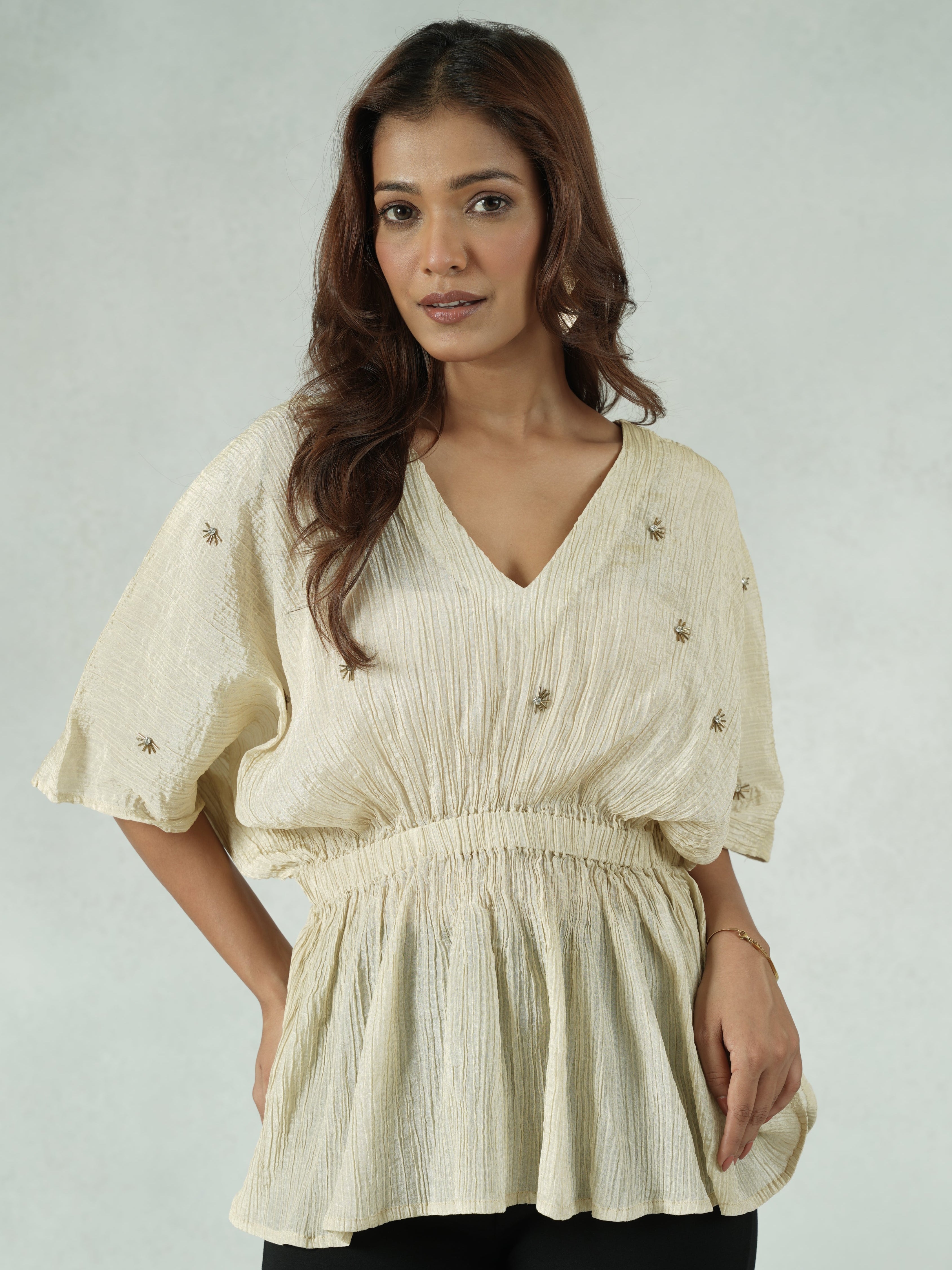 Woman wearing a beige blouse with a plain background