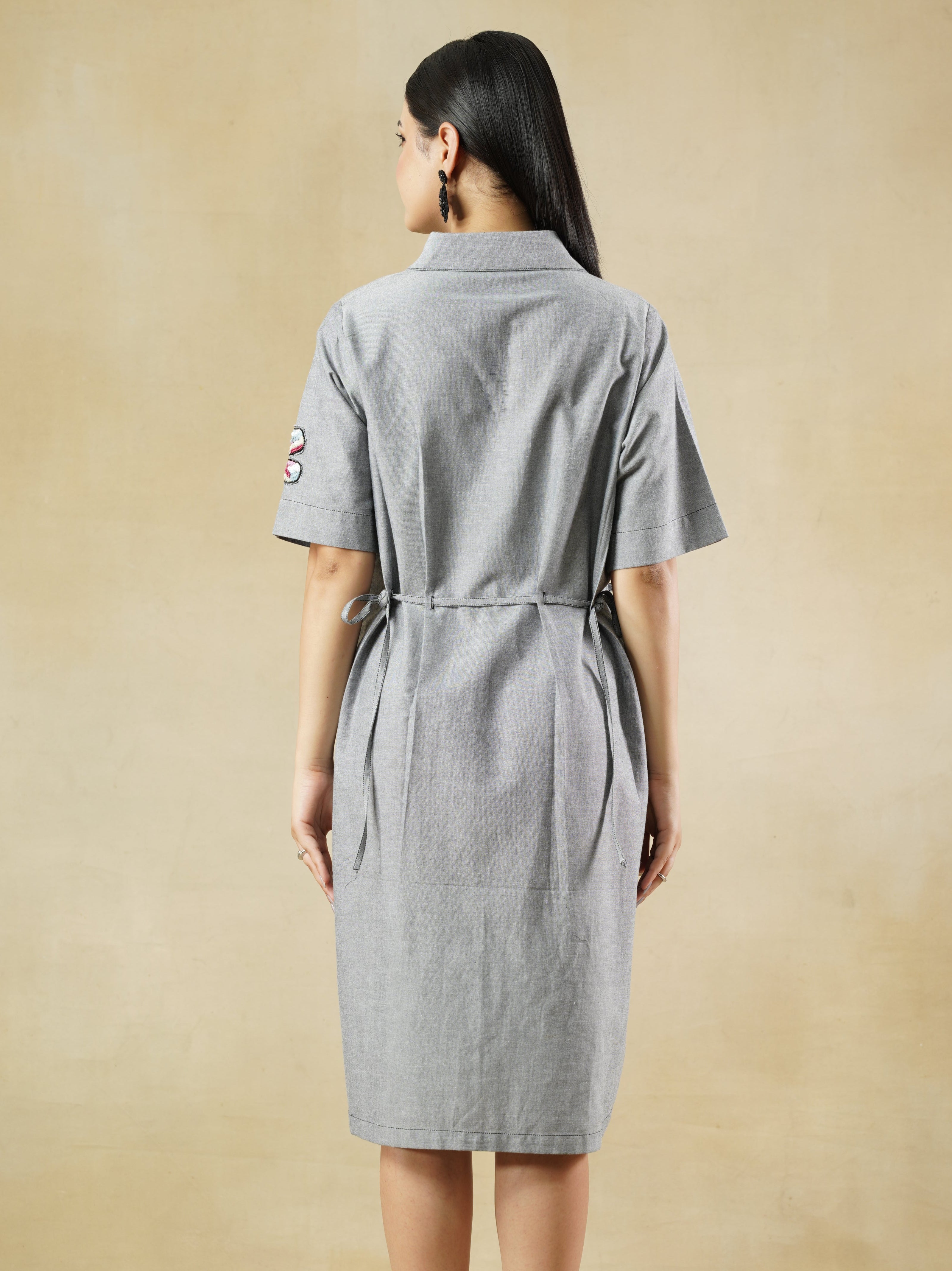 Woman wearing a gray dress standing on a beige floor.