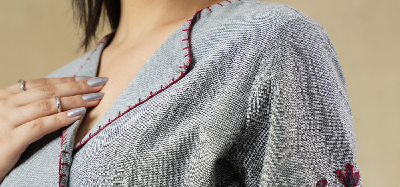 Gray blouse with red floral embroidery on a beige background