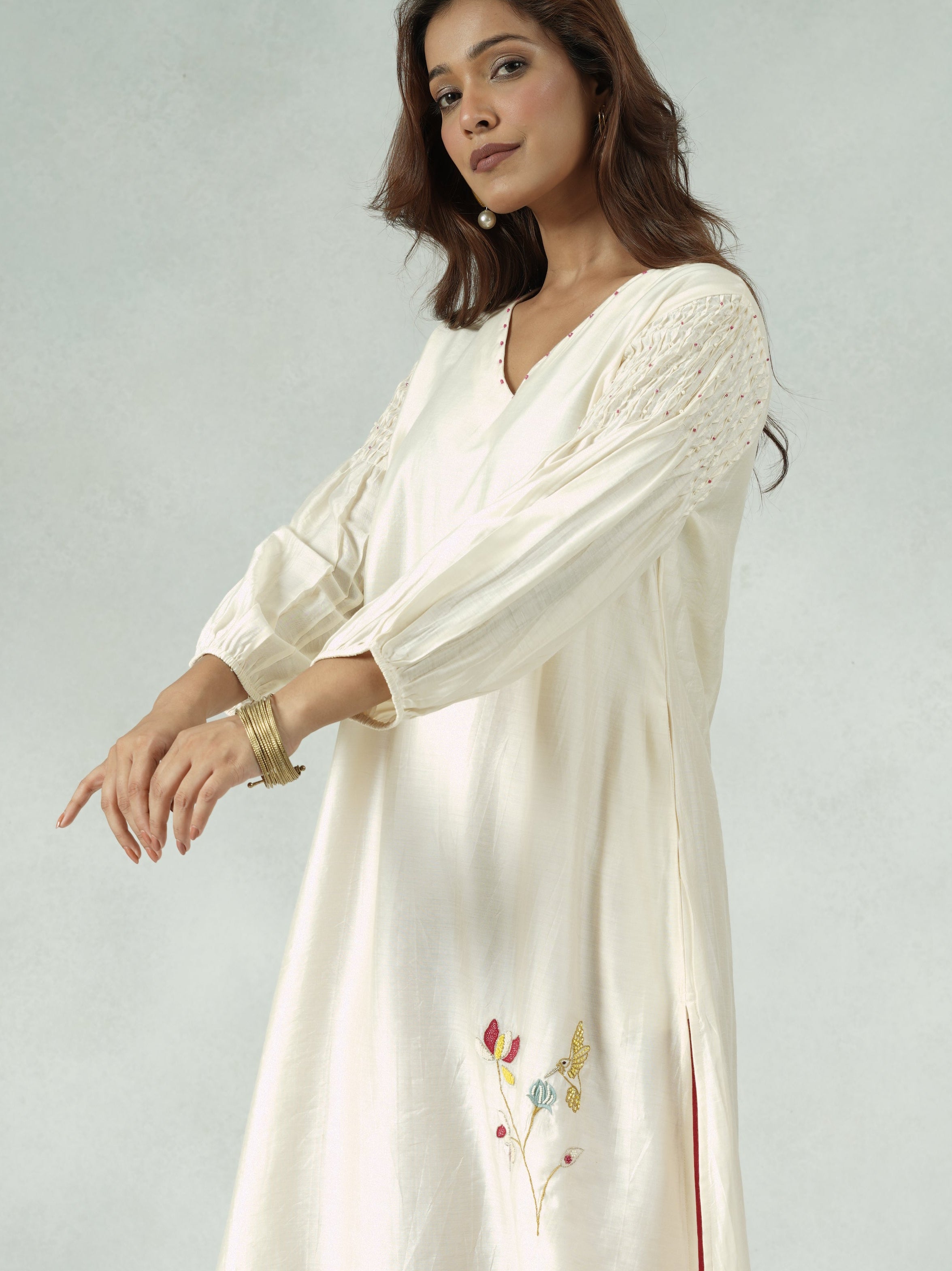 Woman wearing a white outfit with red pants on a plain background