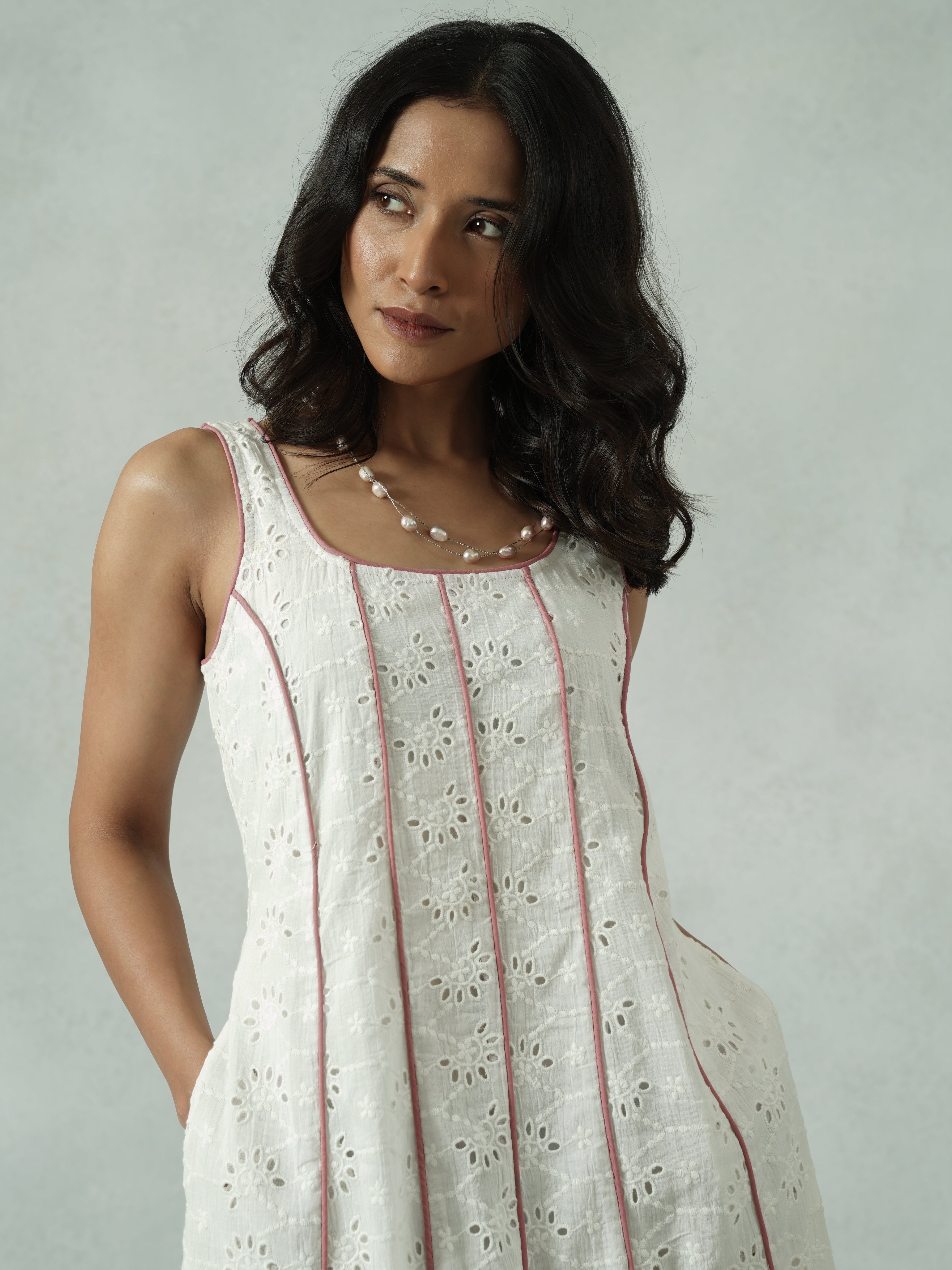 Woman wearing a white dress with red accents against a plain background