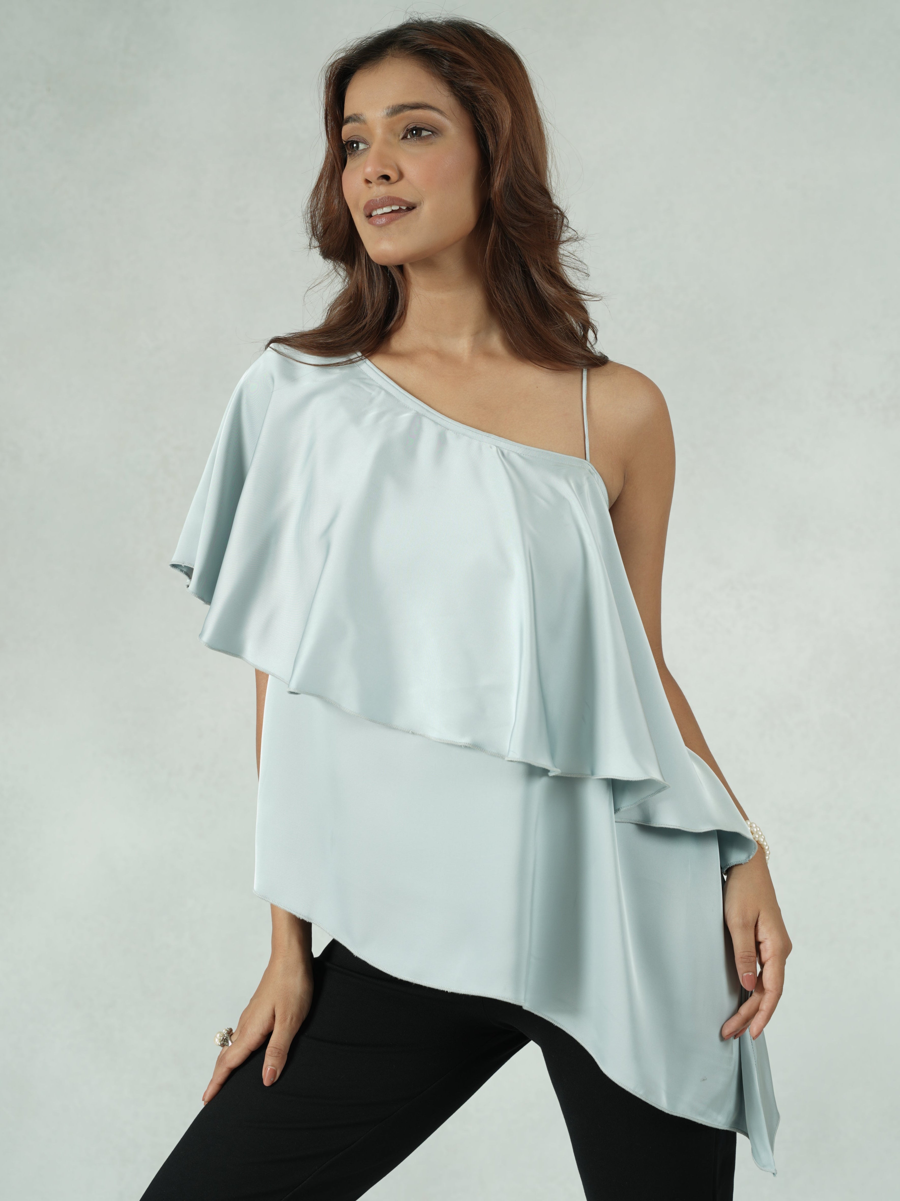 Woman wearing a light blue off-shoulder top on a plain background