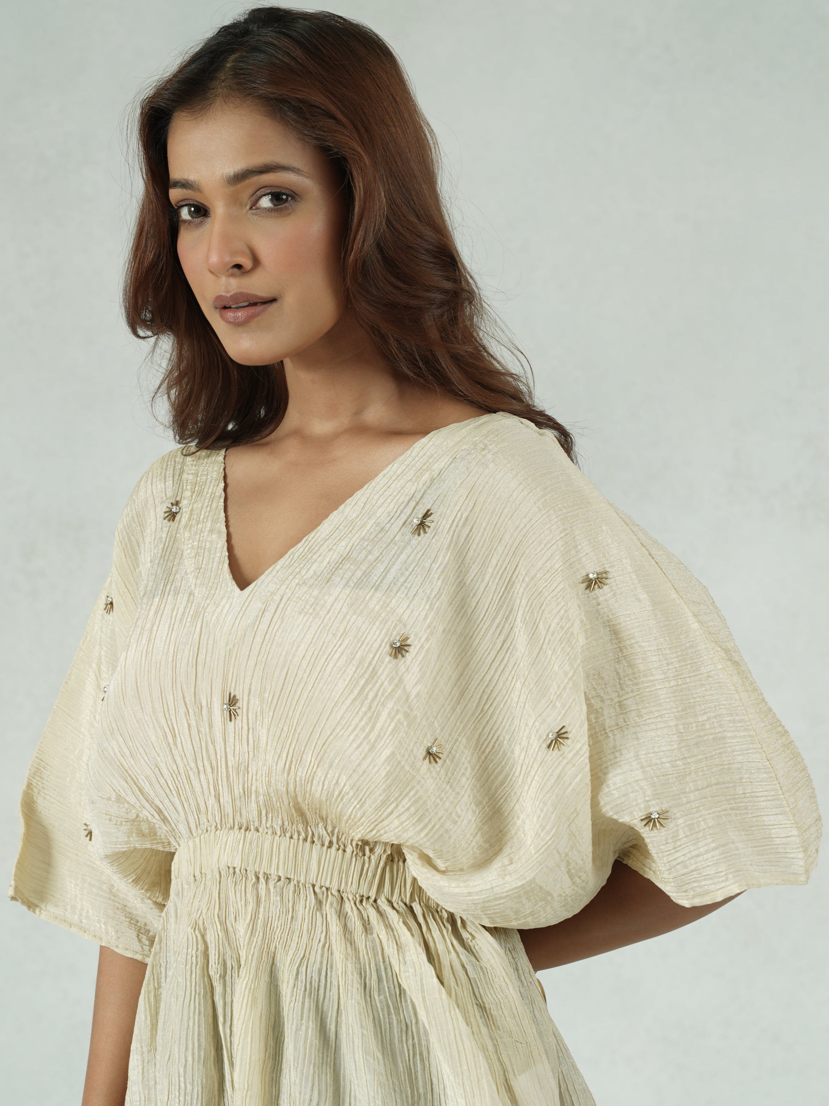 Woman wearing a beige blouse with puffed sleeves on a plain background