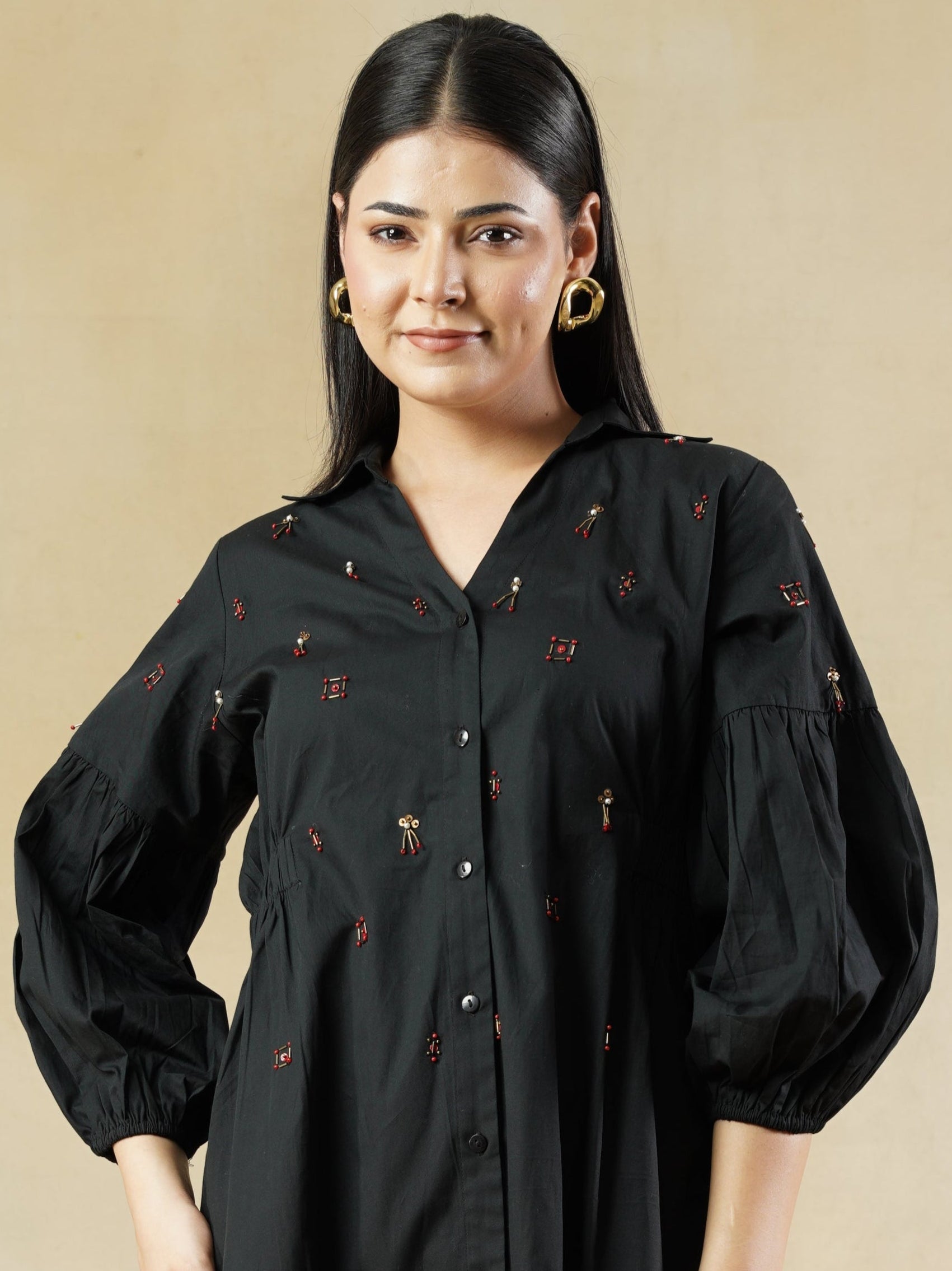 Woman wearing a black dress with floral details on a beige background