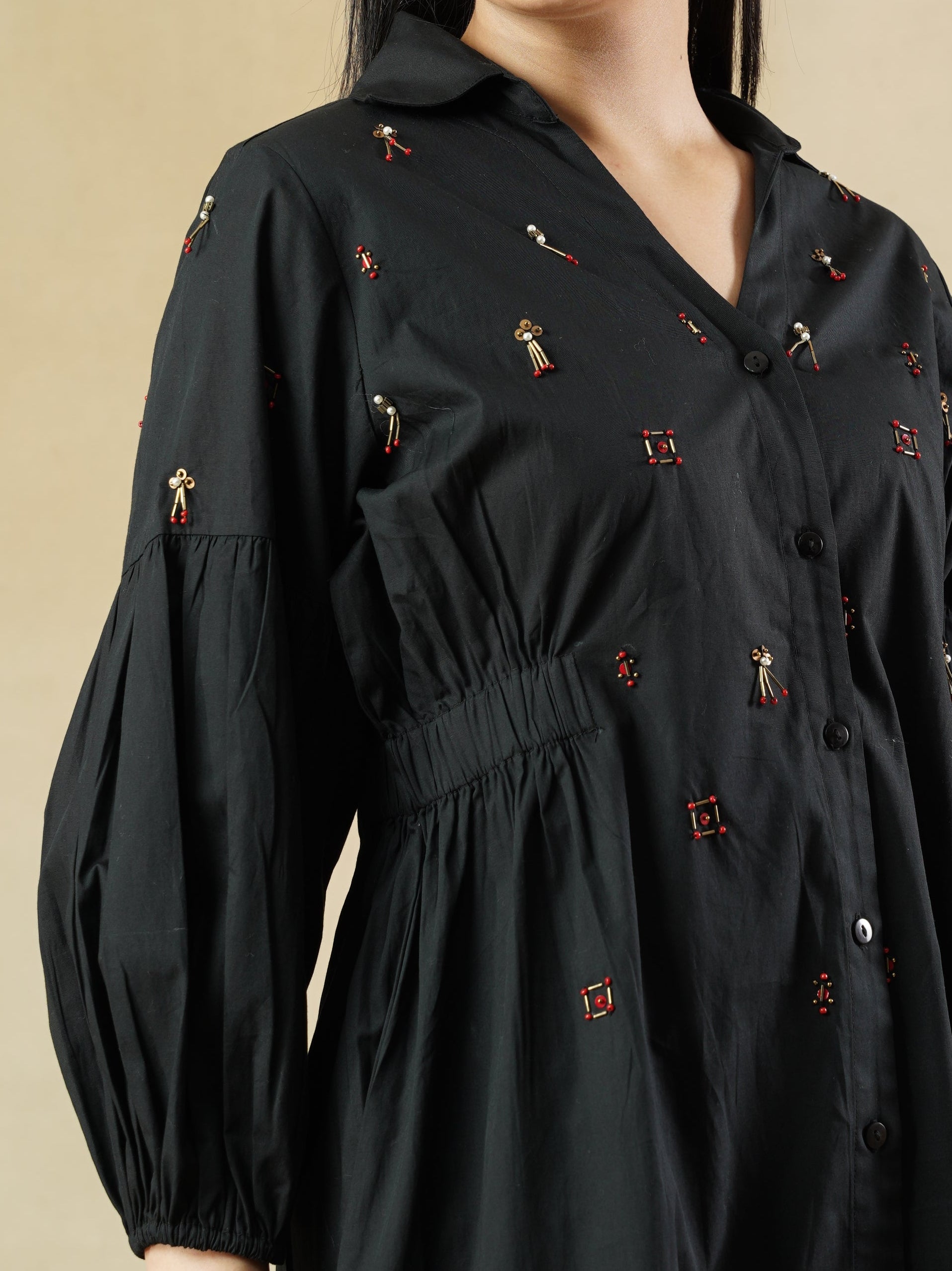 Woman wearing a black dress with small red patterns on a beige background