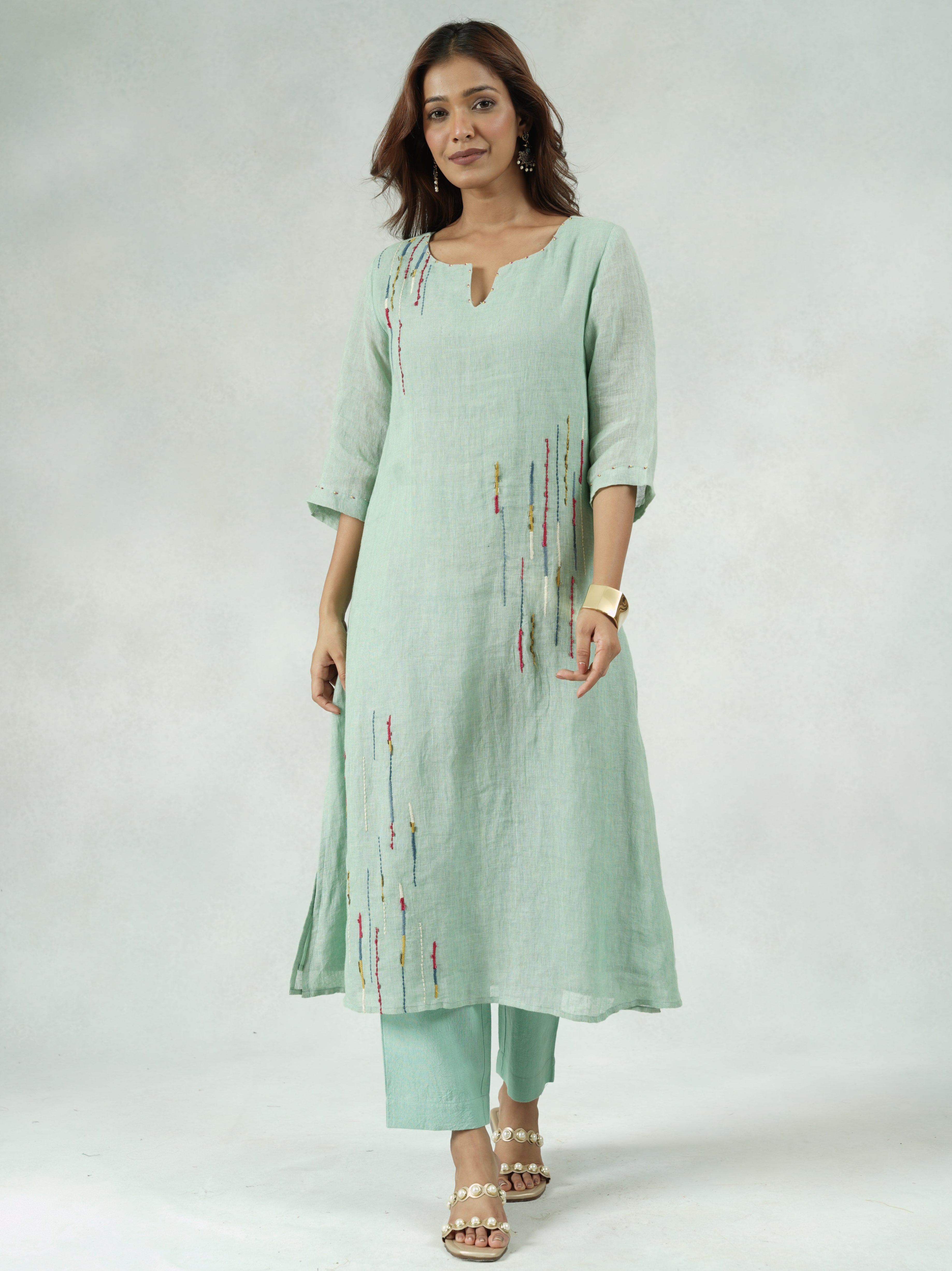 Woman wearing a light green dress with a subtle pattern on a white background