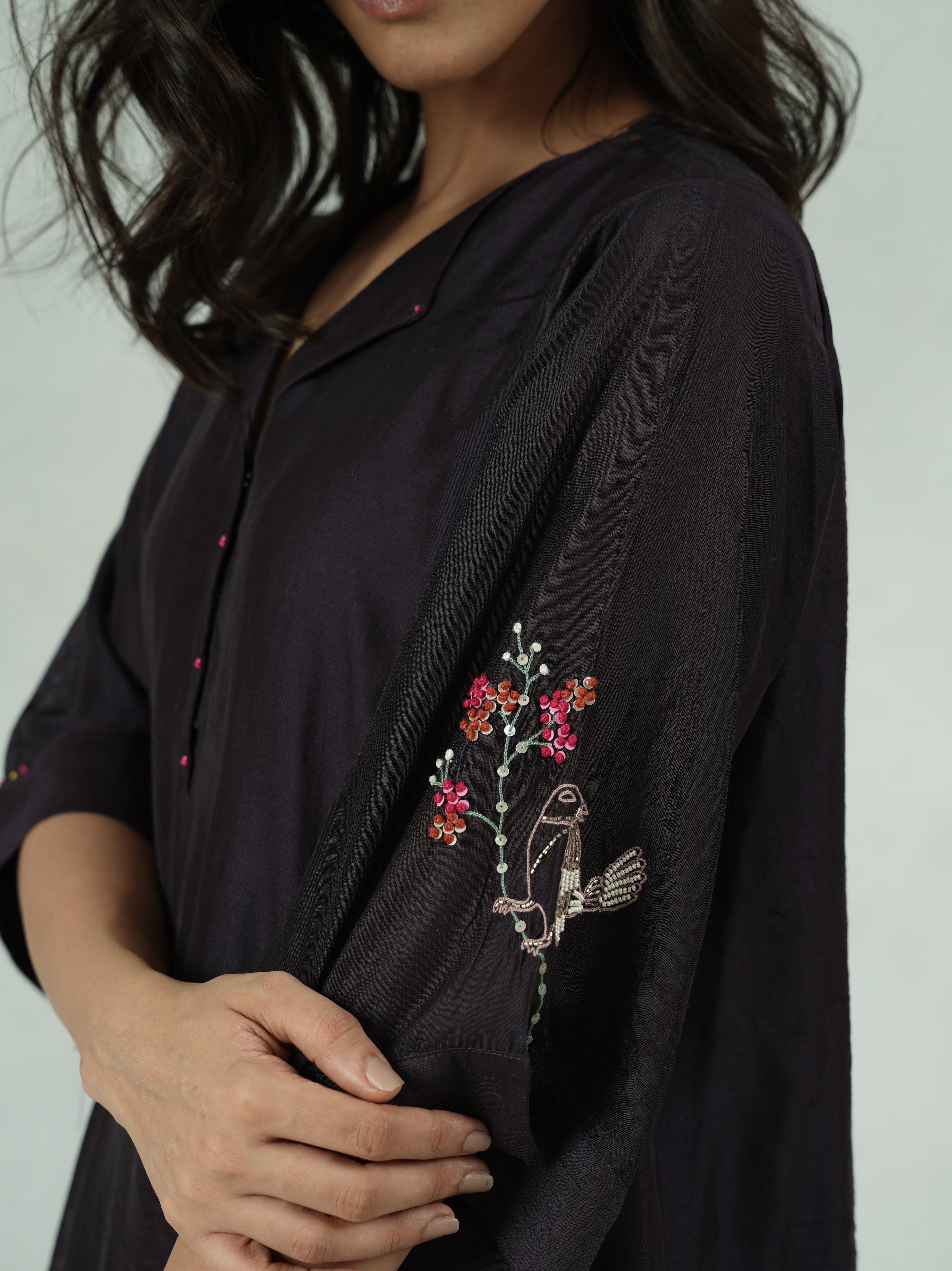 Black outfit with floral embroidery on a plain background