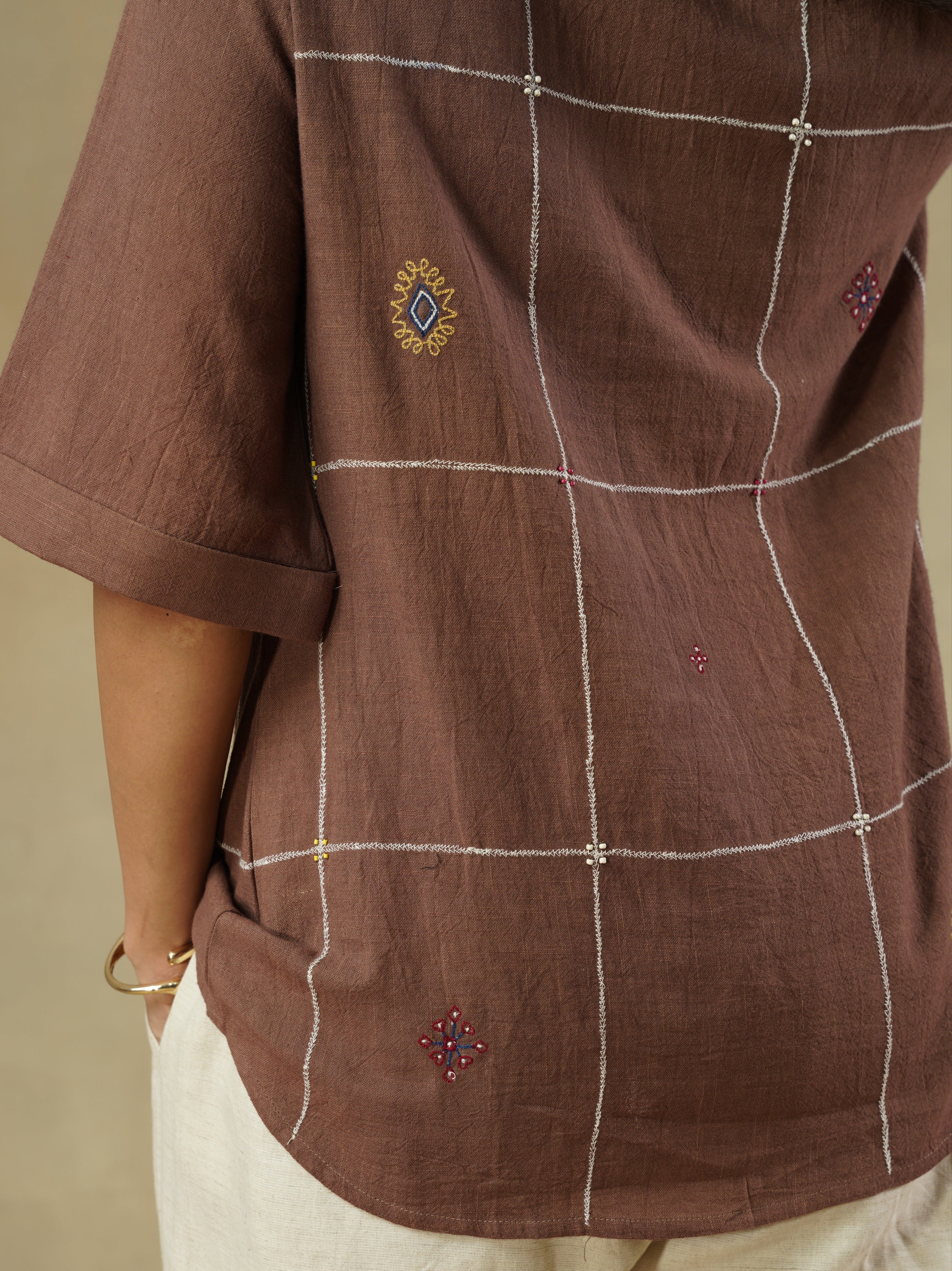 Brown shirt with white embroidery on a beige background