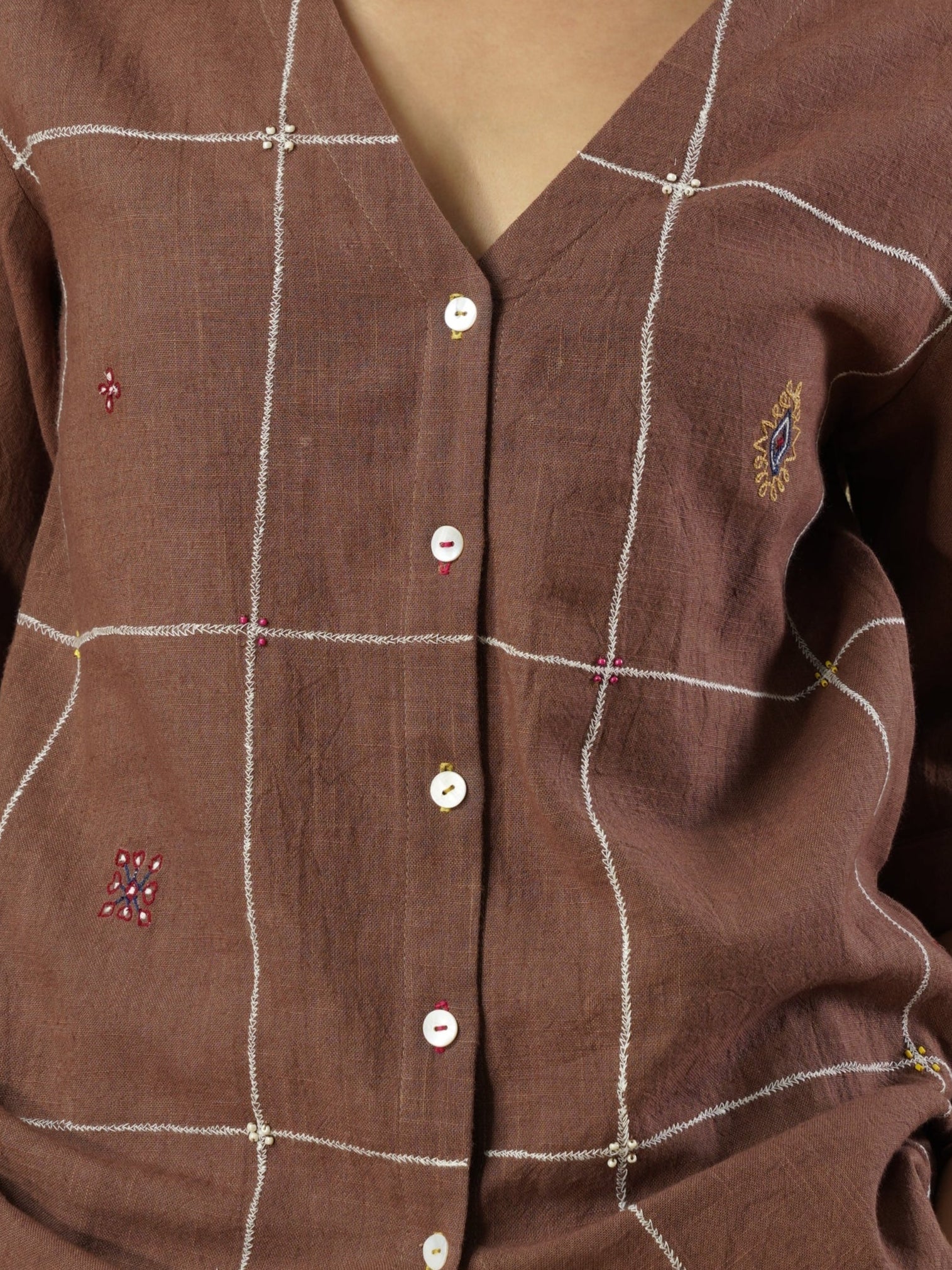 Woman wearing a brown checkered shirt against a beige background
