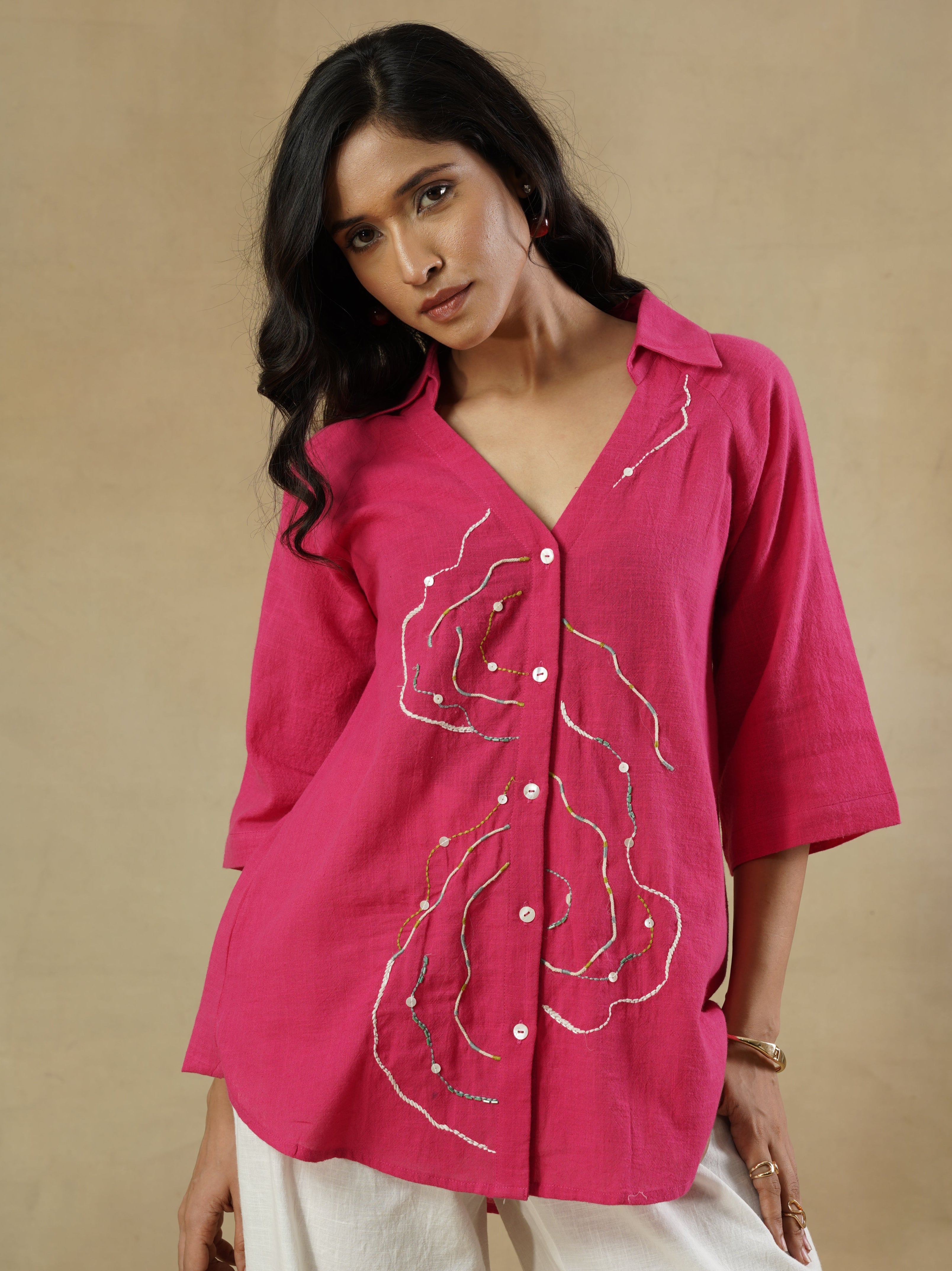Woman wearing a pink embroidered jacket on a beige background