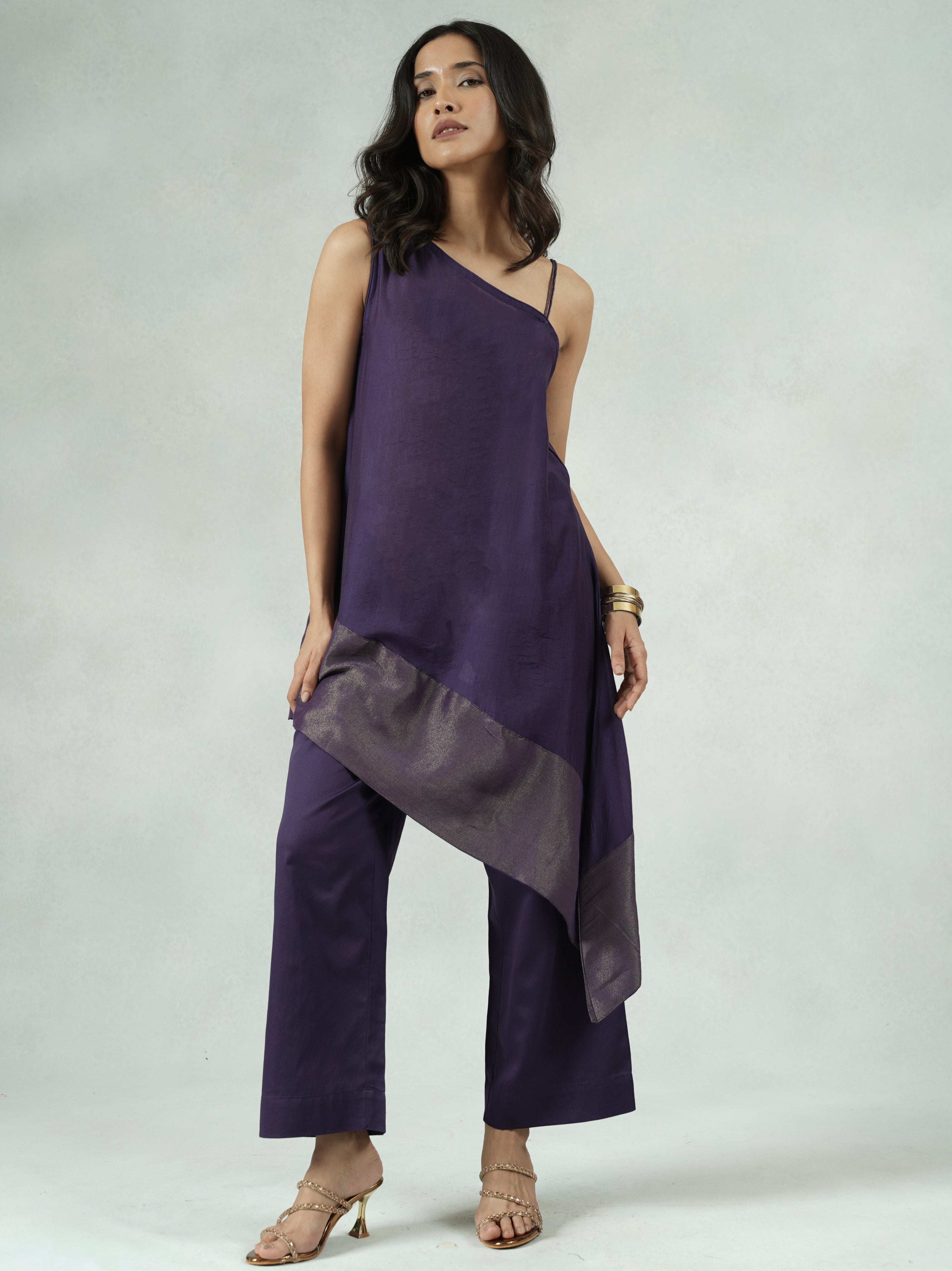 Woman wearing a purple outfit with a layered design on a plain background